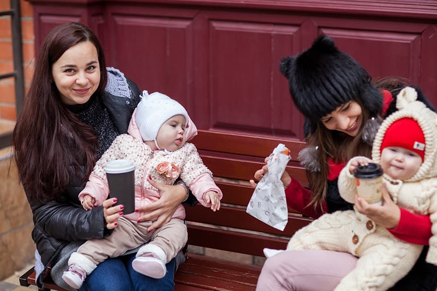 Small Babies with happy moms sitting on the bench