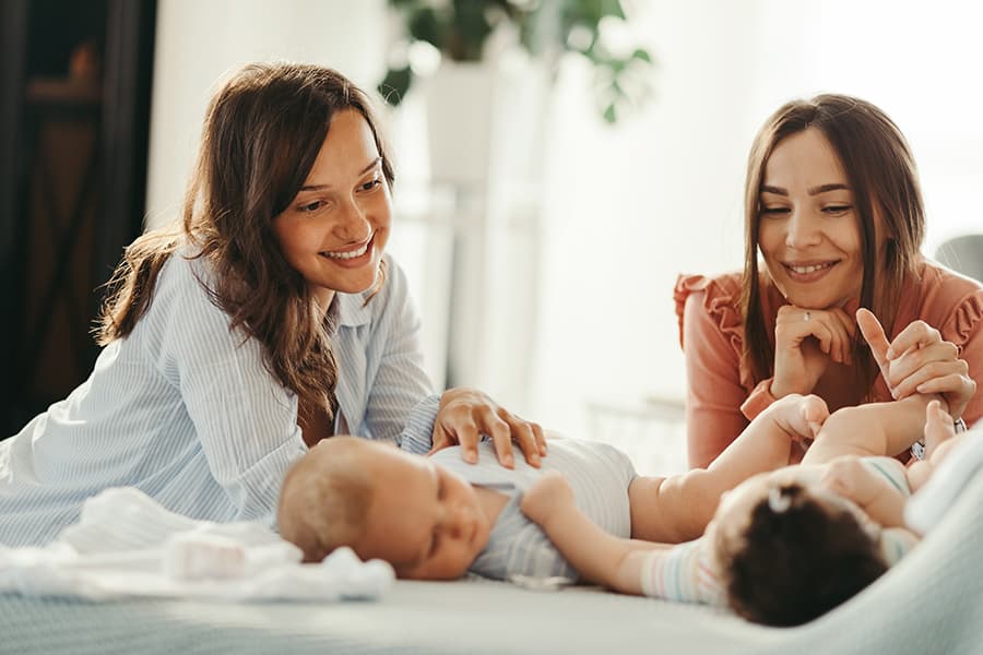 Smiling mothers playing with their babies, enjoying motherhood